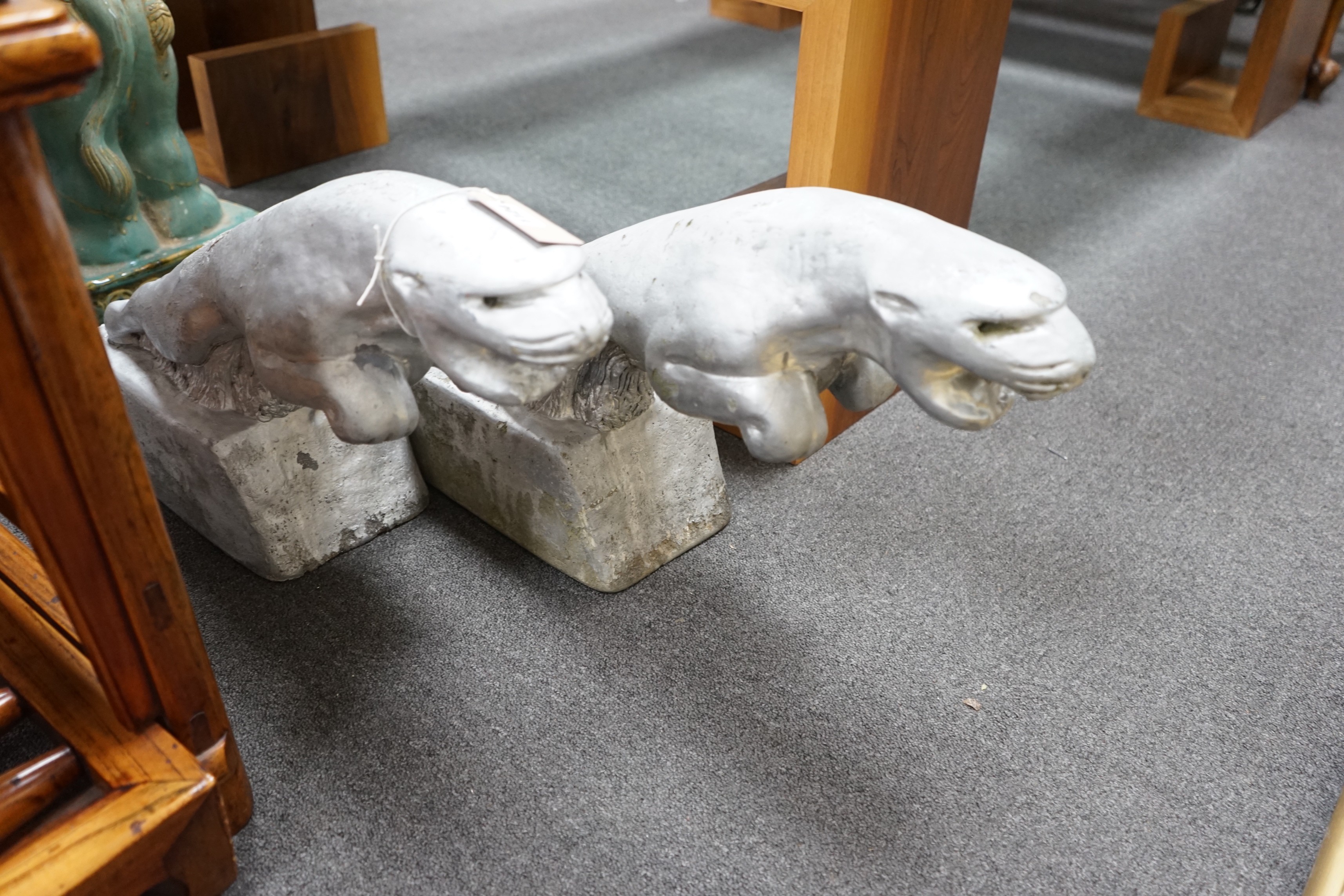 A pair of painted reconstituted stone Jaguars after F.G. Crosby by repute taken from a car dealership, circa 1930, length 60cm, height 36cm